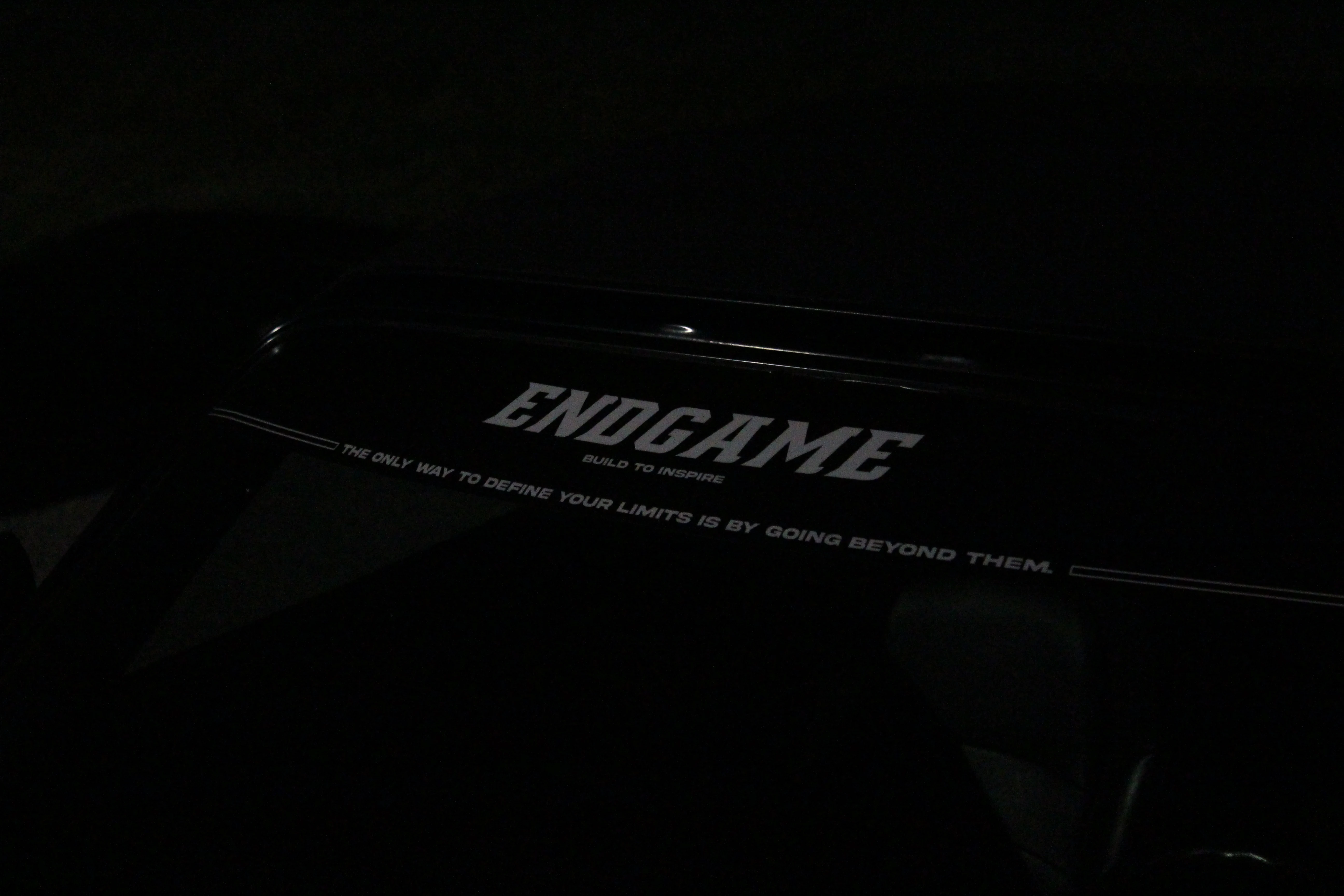 A black license plate frame reading ENDGAME, build to inspire, lit in the dark.