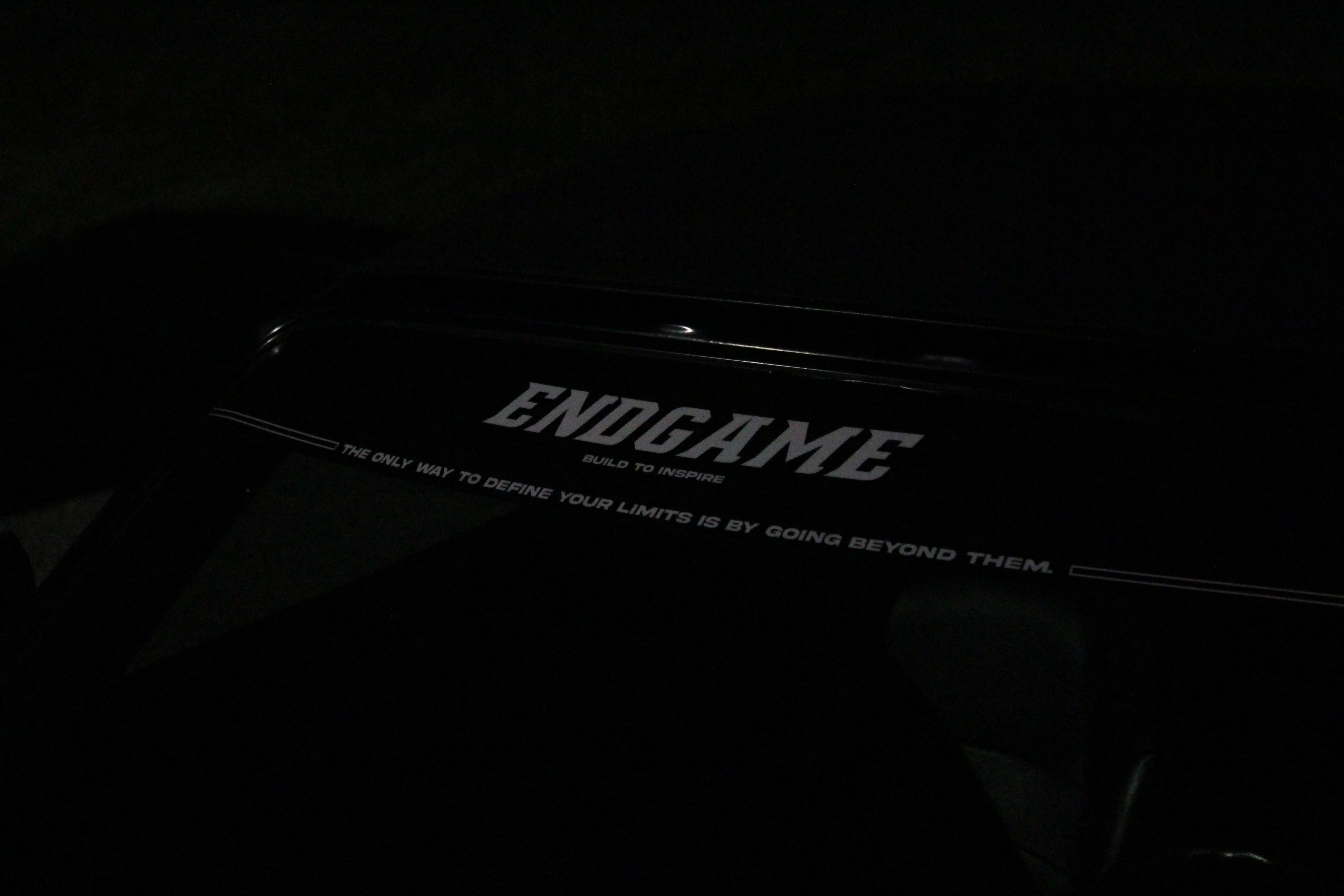 A black license plate frame reading ENDGAME, build to inspire, lit in the dark.