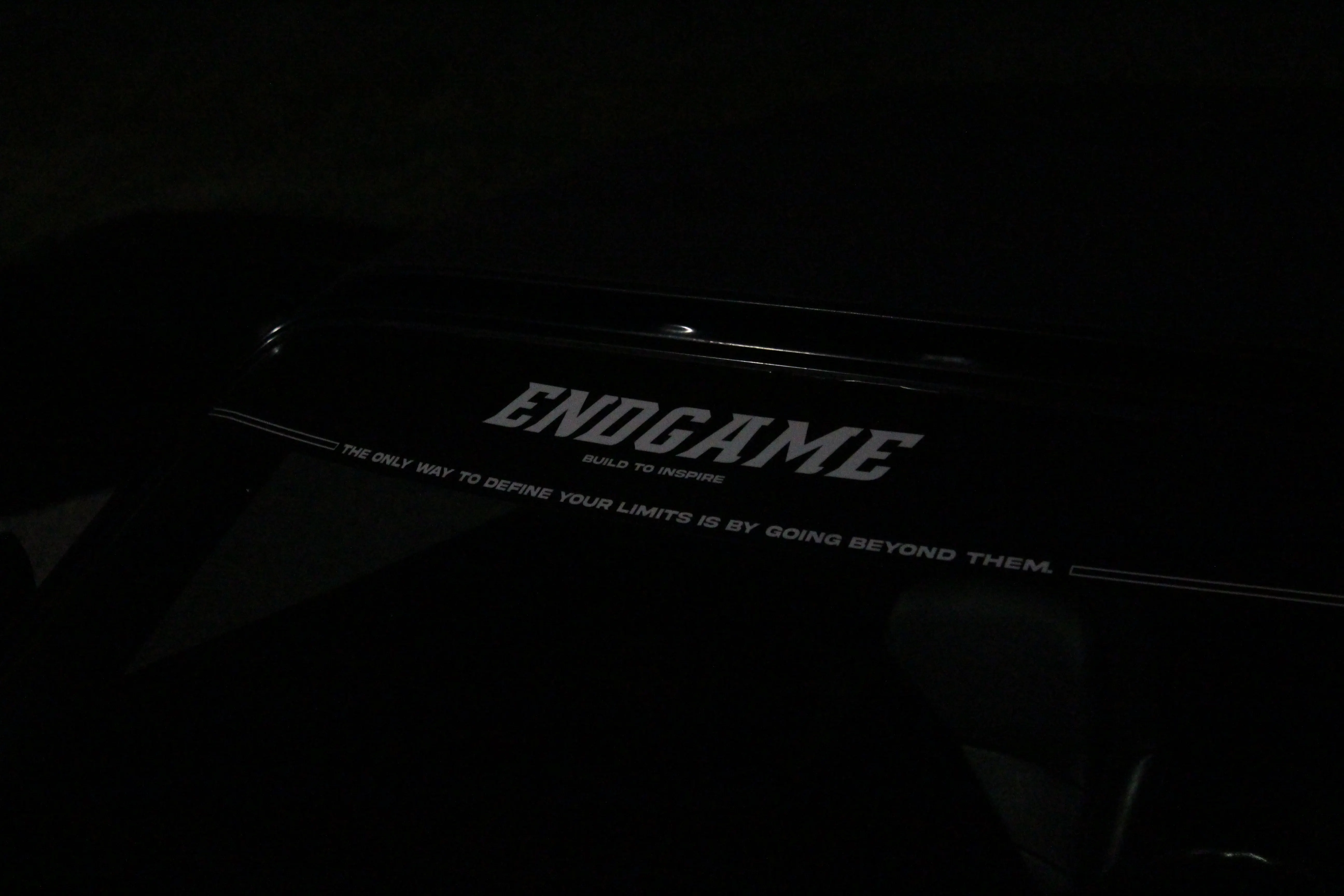 A black license plate frame reading ENDGAME, build to inspire, lit in the dark.