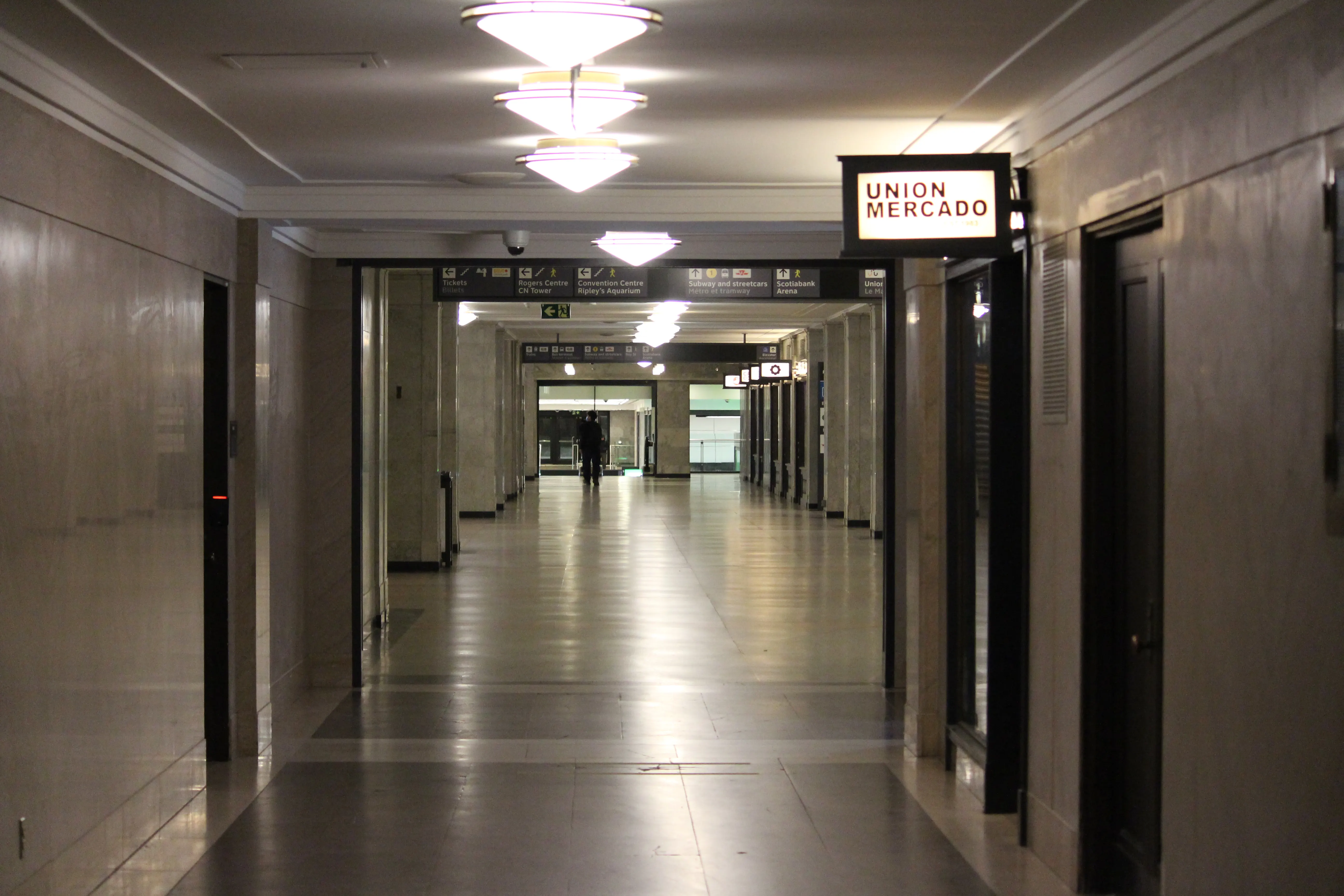 Empty corridor inside Union Station Toronto with stepped ceiling lights and an illuminated "Union Mercado" sign overhead.