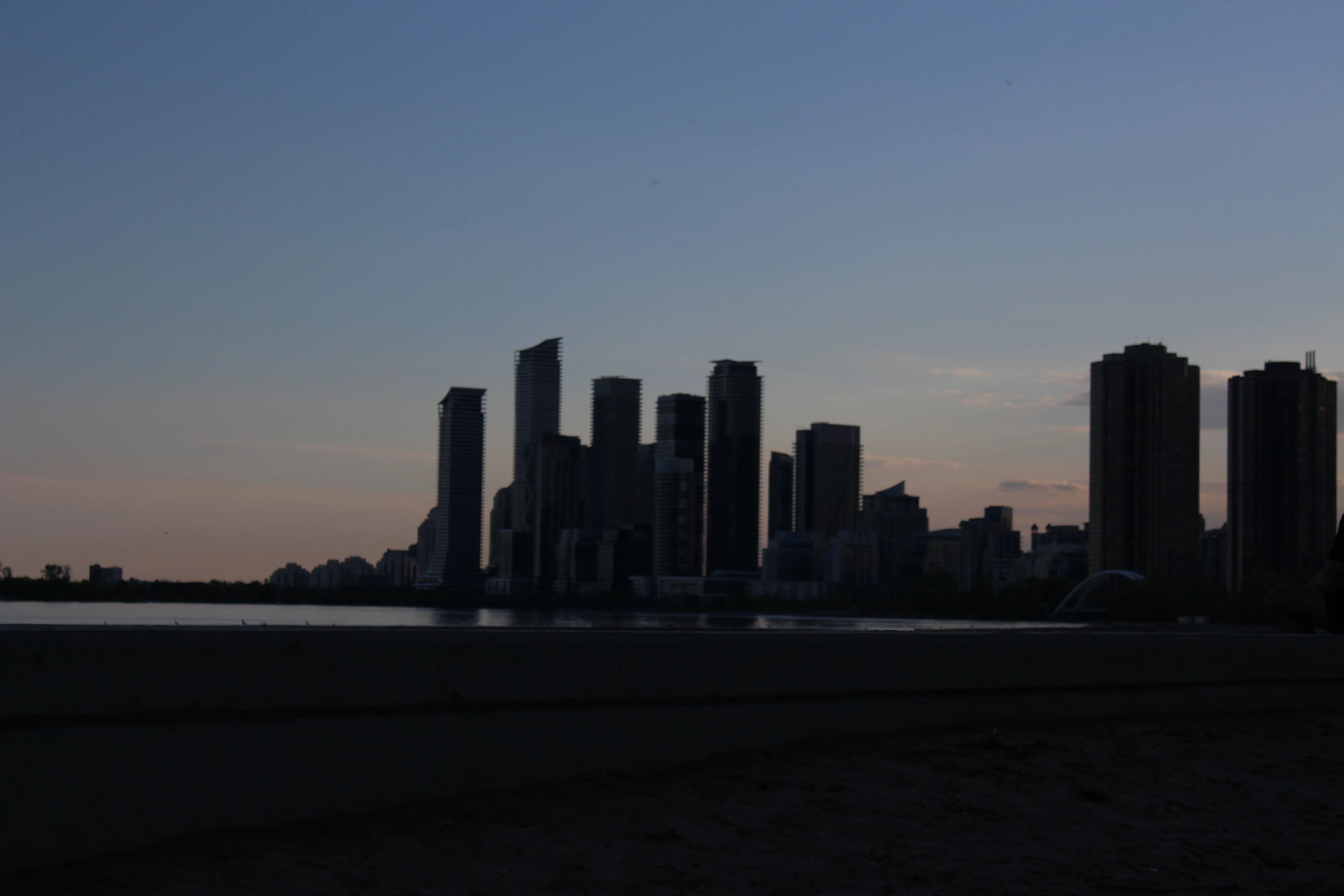 Cluster of condominium towers silhouetted against a pale dusk sky over the lake.