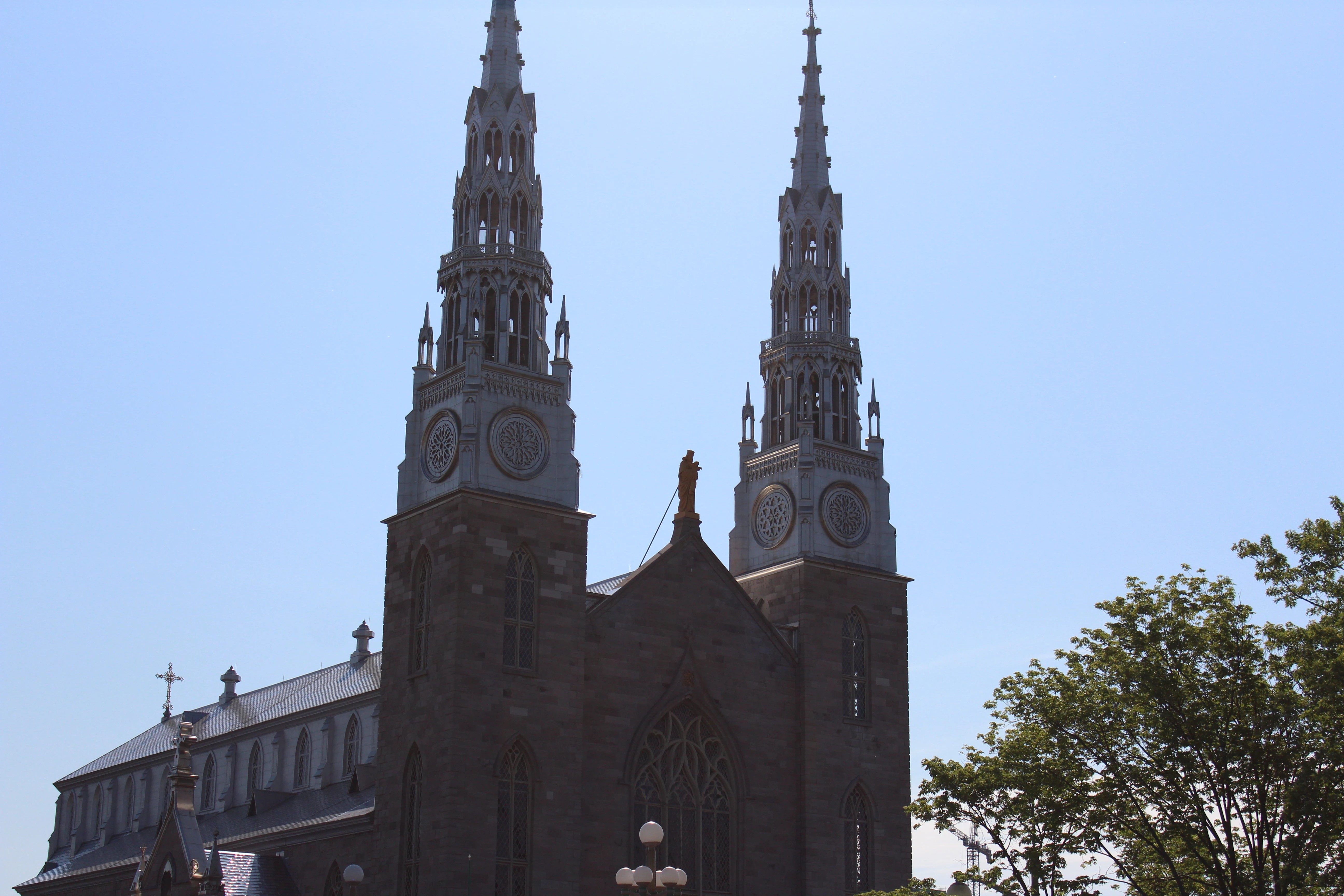 Twin gothic spires of a stone cathedral against a pale summer sky.